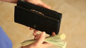 Women's hands hold a money clip with dollars