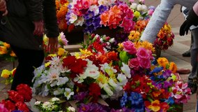 Ungraded: Woman chooses artificial flowers at an outlet in the open air.  