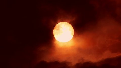 Big sun disk in sunset in cloudy sky timelapse. horror and terror background. ecology and pollution concept. Red moon. Wolf Night background. red smoky sky with a big red sun.