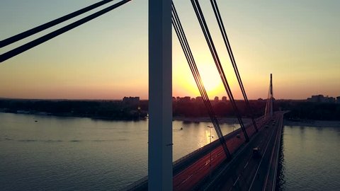 Aerial shot of the bridge over the river. Sunset drone video shot of the traffic on the bridge.