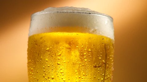 Cold Light Beer in a glass with water drops. Craft Beer close up. Rotation 360 degrees. 4K UHD video 3840x2160