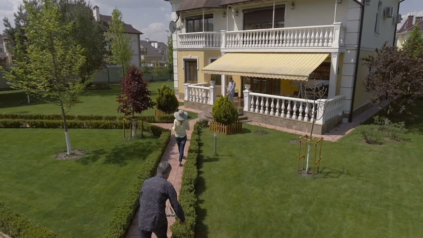 Three people moving in the green garden. aerial
