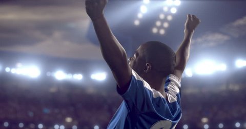 4k footage of a soccer player in celebrating a goal during a soccer game on a professional outdoor soccer stadium. Players wear unbranded uniform. Stadium and crowd are made in 3D.