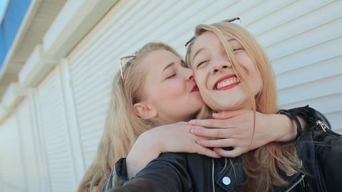 Two young beautiful girlfriends blonde fun and coquettish posing in front of the camera. Do selfie. Spring