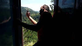 Man with cellphone leaning out of door during train ride, super slow motion 240fps
