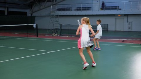 Double team of young boy and girl playing tennis with skilled woman player
