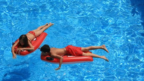 Children, a boy and a girl are floating on inflatable mattresses in the pool. view from above.