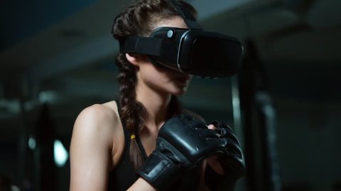Young attractive woman boxing in VR 360 headset training for kicking in virtual reality. Slowmotion shot