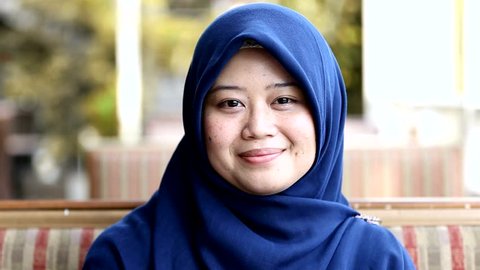 Portrait of muslim south east asian woman with hijab is smiling at the cafe