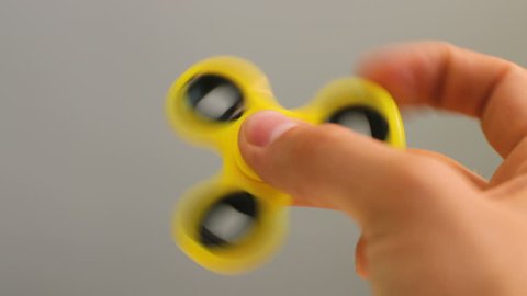 Yeloow spinner fidget device in hand.Man playing with new spinning toy.Popular gadget with bearings in the middle