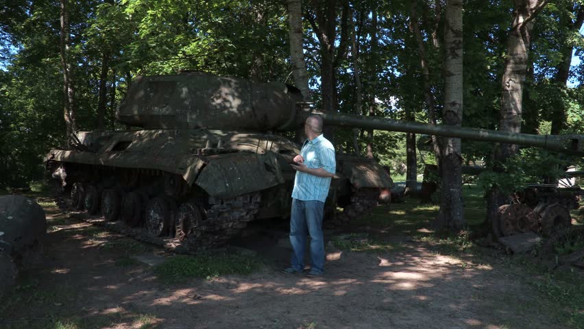 Tourist using tablet at the tank of the second world war