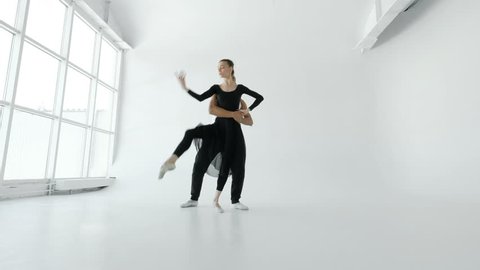 Girl and boy dancers warm up before the performance in a white room with a large window 20s 4k.