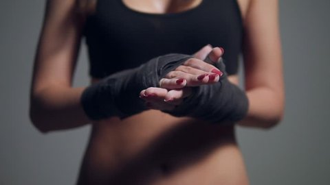 Closeup view of young beautiful fit woman dusting powder on her hands wrapped in boxing tapes as she prepares for a workout at the gym. Slowmotion shot