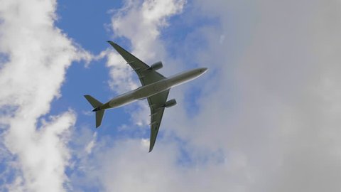 Commercial passenger airplane flying overhead on sunny day. UltraHD stock footage.