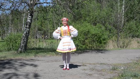 The girl in a national Russian (Belarusian) suit dances against the background of the Belarusian nature. Ethno style. Russian (Belarusian) folklore.