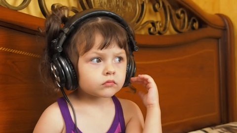 A little girl with headphones. A child listens to audiobooks.