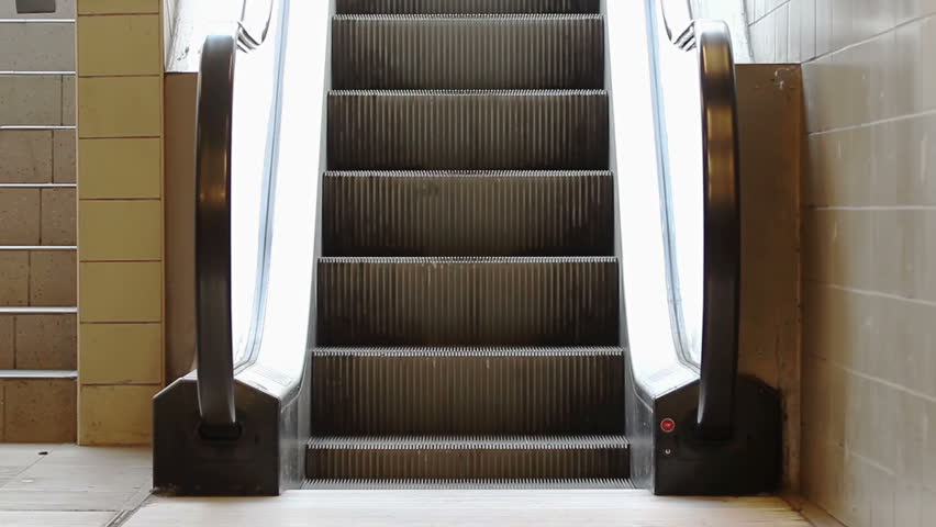A young girl stepping on escalator and moving upstairs towards the light