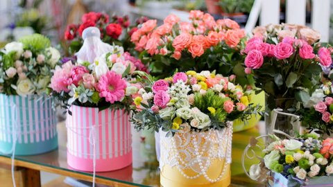 Flower shop, on the show-window, there are a lot of bouquets of flowers from pion-shaped roses, floral stylish compositions in colorful boxes with different flowers