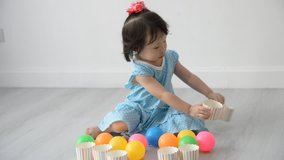 Asian girl playing colorful balls at home. 