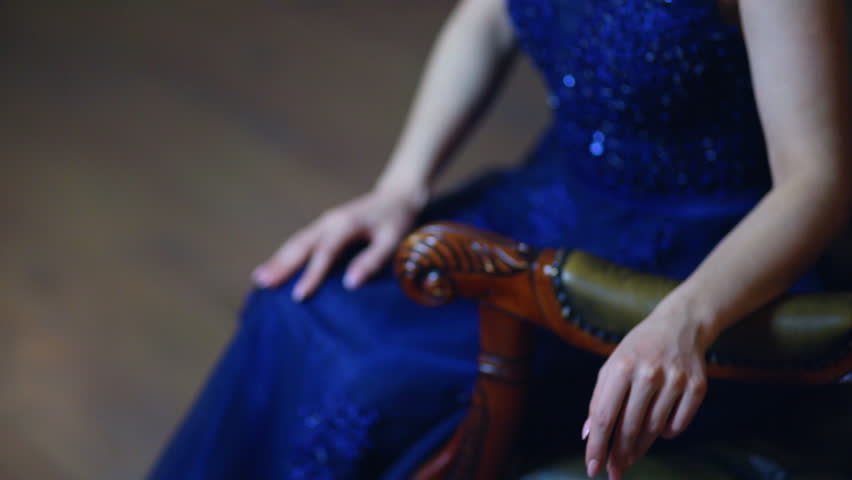 Beautiful girl in a sexy long dress, make-up and crown posing for a photographer in a classic interior