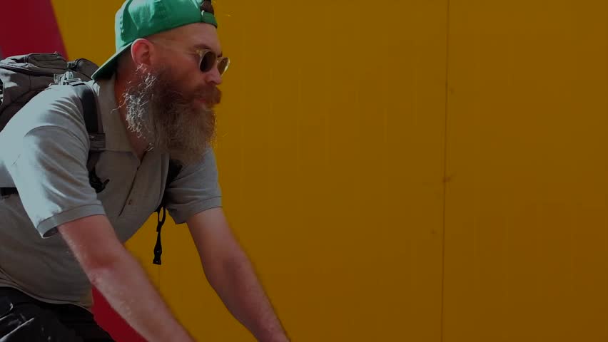 Bicyclist With a Big Beard Riding on a Background of Yellow Wall