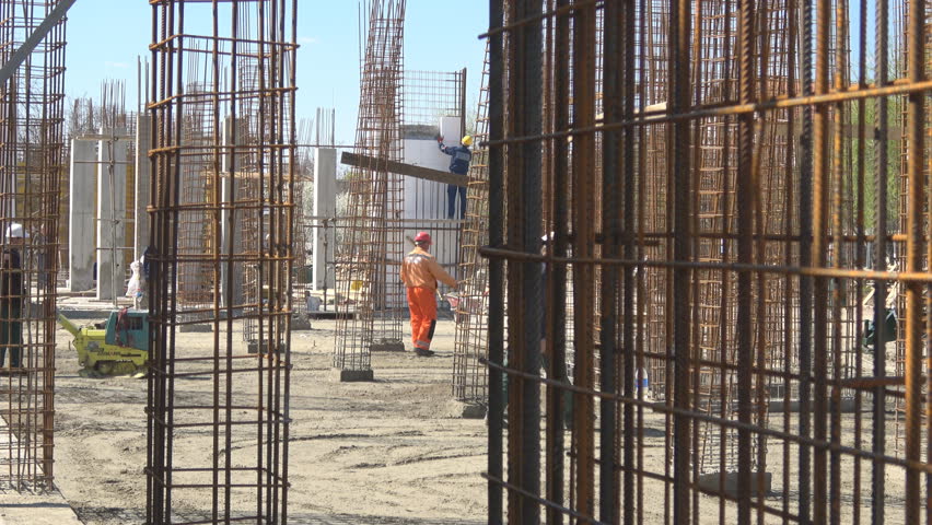 Wire armature on construction site with Unrecognizable workers in the background
,Handheld camera Balanced Steady shot 
 | Shutterstock HD Video #28421509
