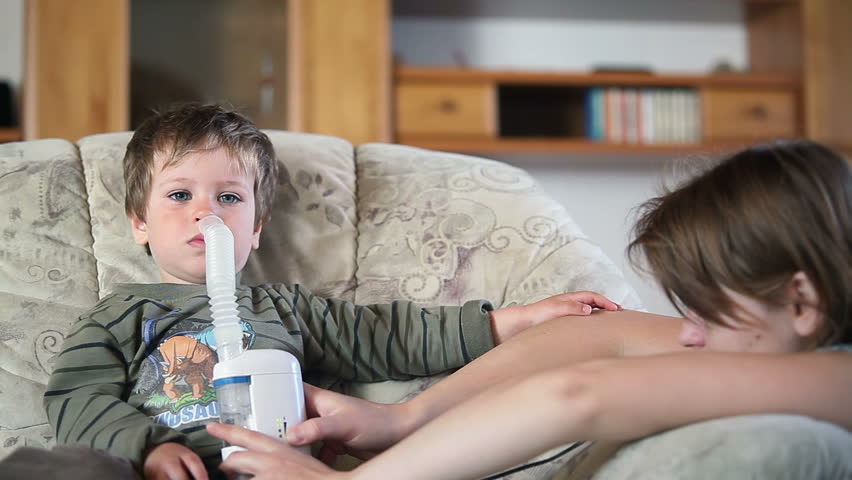 Mother and sick little boy using nebulizer to inhale medicine