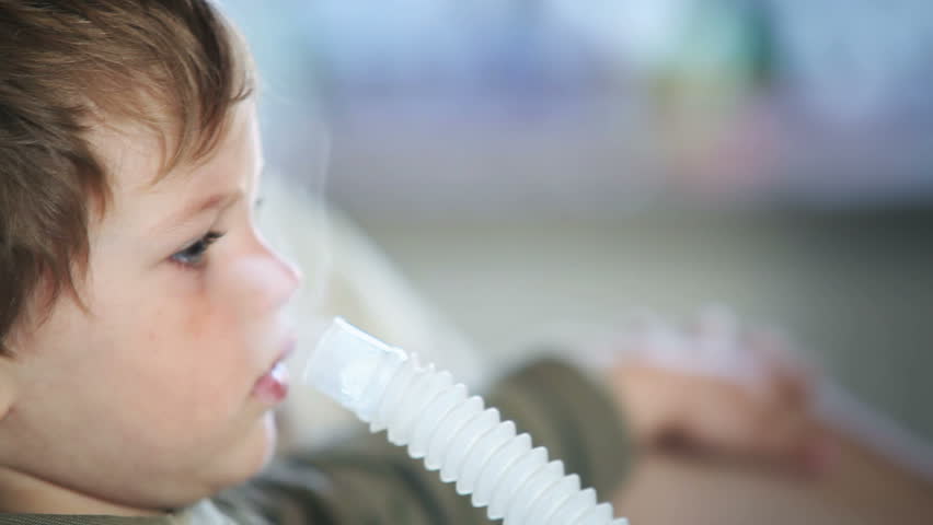 Little boy using nebulizer to inhale medicine, close up side view