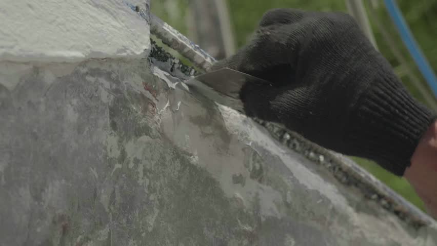 Hand in black working glove puts the putty on side of yacht. Live camera. Close-up