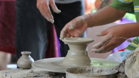 A potters  guiding a child to work with the ceramic wheel