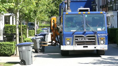 VANCOUVER, BC, JULY 2017: A new modern garbage truck comes to collect the trash in a suburban townhouse community.