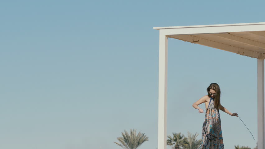 Beautiful lady ties her dress on blue sky background
