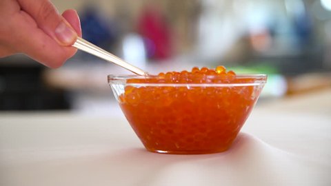 Red caviar being scooped from glass bowl