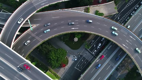 Rotating drone view into the center of busy multilevel interchange flyover in Shanghai showing afternoon traffic coming from the elevated roads