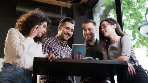 Happy Trendy Group Of Friends Standing Together Around A Bar Table Passing iPad Looking At Video Laughing Smiling Talking On Phone At Restaurant Slow Motion Shot On Red Epic 8K