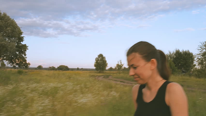 The girl is walking along the field