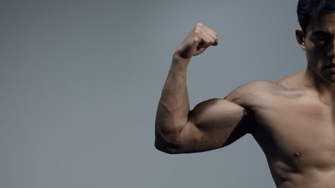 Male fitness model flexes his bicep and stretches out his arm. Close up. 