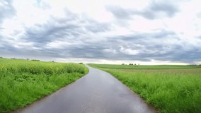 Driving on a country road with a nice cloudscape after a rainshower with high contrasts. POV Video Footage in 4K from germany