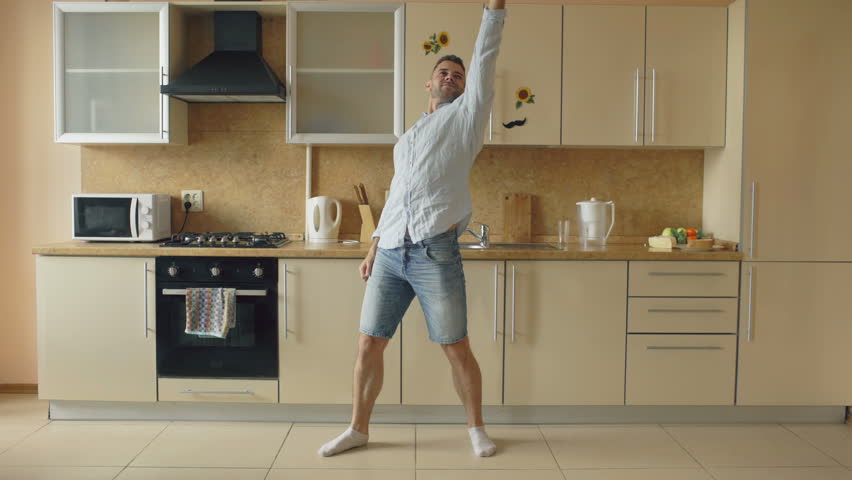 Handsome young funny man dancing in kitchen at home in the morning and have fun on holidays Royalty-Free Stock Footage #28456333