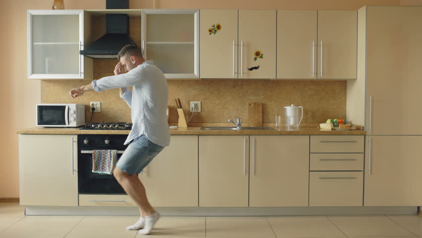 Handsome young funny man dancing in kitchen at home in the morning and have fun on holidays Royalty-Free Stock Footage #28456357