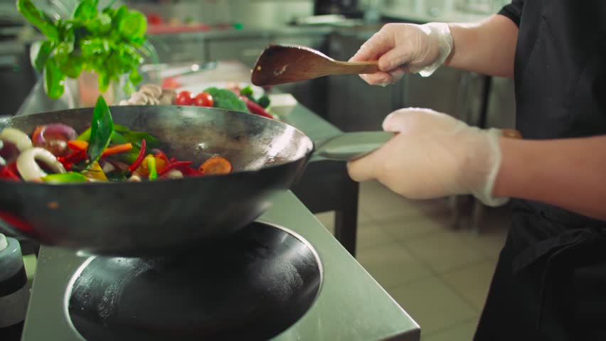 close-up chef actively working in the kitchen of an Asian restaurant mixed colorful vegetables are roasted in a wok in slow motion Royalty-Free Stock Footage #28469797