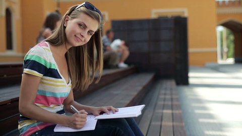 Happy female student doing homework in the city, stabilized shot