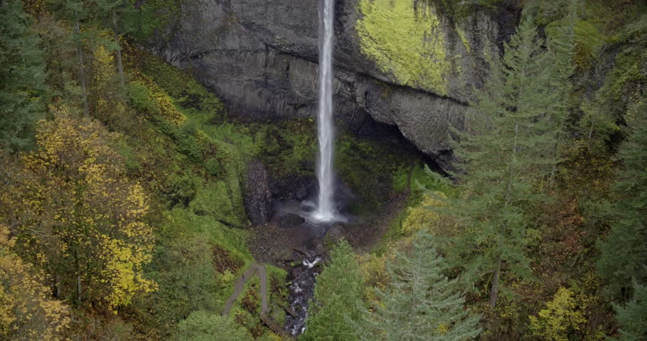 Aerial drone view flying through trees to a waterfall during autumn in Portland, Oregon