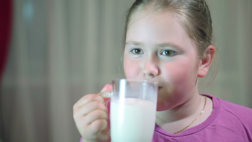 Child drinking milk from glass. Girl with beautiful blond hair. A child 8 years old | Shutterstock HD Video #28489414