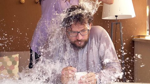 Woman doing prank on boyfriend splashing water on his head super slow motion closeup