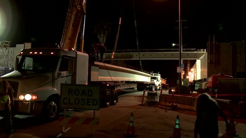 Los Angeles, California-2010s: Huge steel girders are delivered during work on a freeway overpass at night in Los Angeles in time lapse.