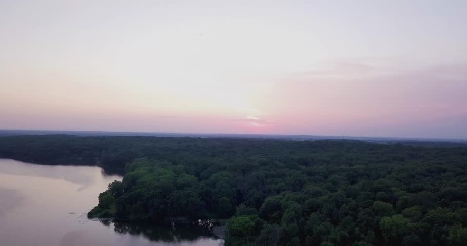4K Aerial shot going over trees towards the sunset