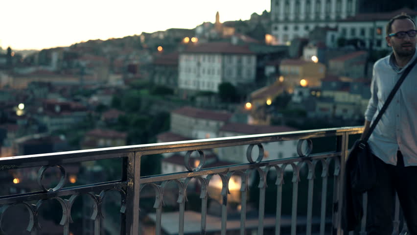Young man taking photo of view standing on bridge in Porto, Portugal 
