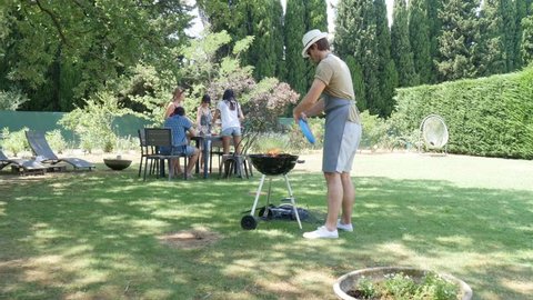 group of happy and cheerful young people having fun around barbecue grill during summer holiday party outdoor in the garden