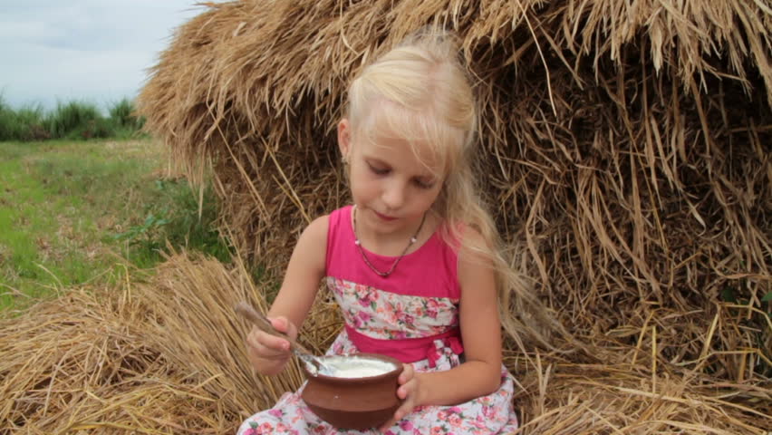 Pretty girl eats sweet yogurt from a clay cap. Healthy lifestyle in summer on farm. Natural eco  food. Happy childhood in a village.